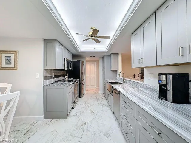 Kitchen featuring gray cabinetry, a tray ceiling, and appliances with stainless steel finishes