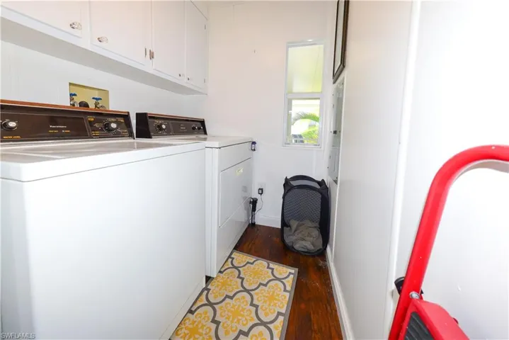 Laundry room featuring washer and dryer, cabinet space, and dark wood-type flooring