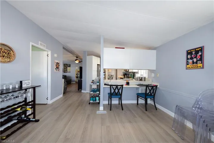 Kitchen with light countertops, a ceiling fan, white cabinetry, light wood-style floors, and a breakfast bar
