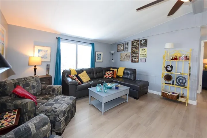 Living room featuring vaulted ceiling, wood finished floors, and ceiling fan
