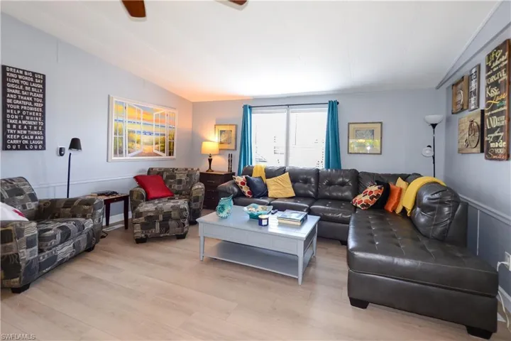 Living room featuring vaulted ceiling, light wood-style flooring, and a ceiling fan