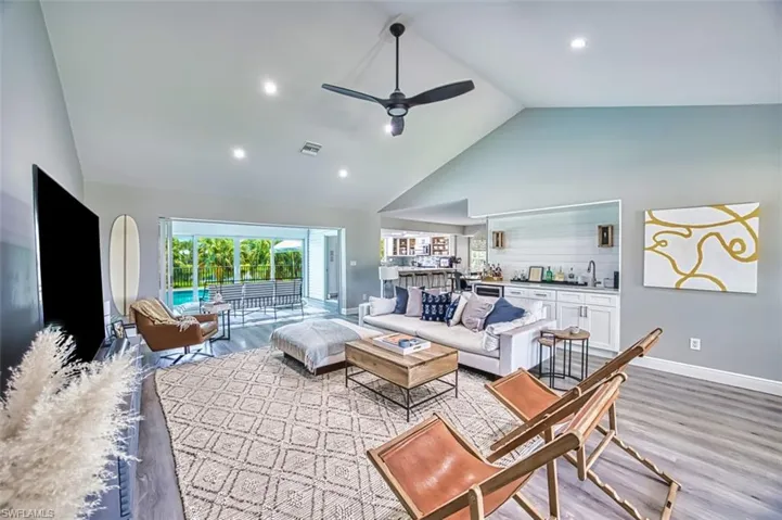 Living room with high vaulted ceiling, a ceiling fan, lvt flooring, and recessed lighting
