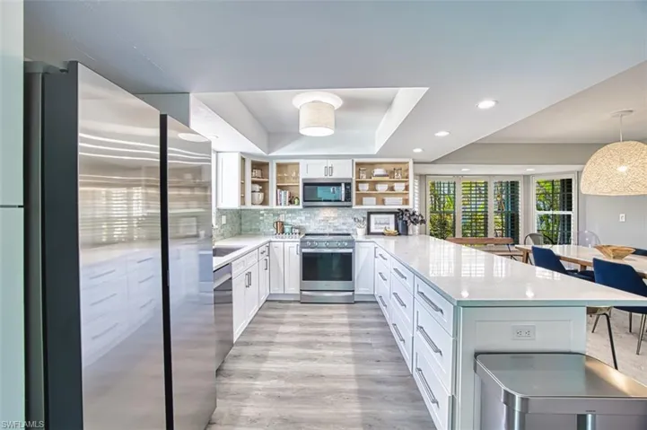 Kitchen featuring appliances with stainless steel finishes, open shelves, a peninsula, a tray ceiling, and white cabinetry