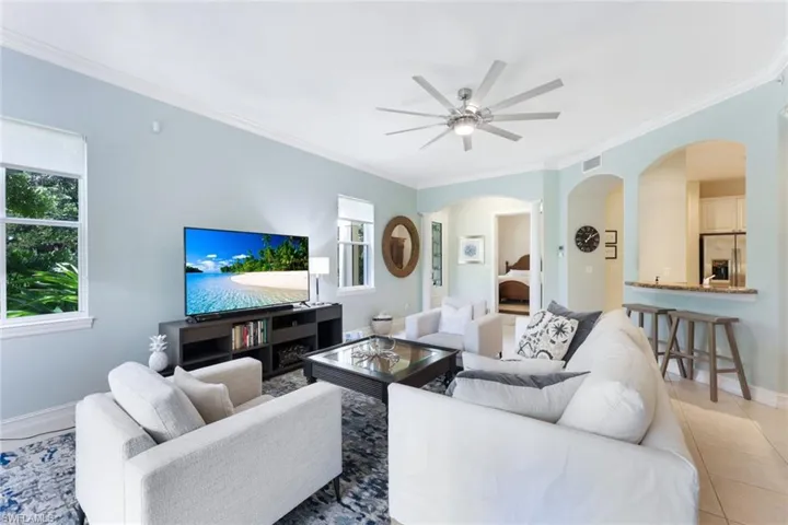 Tiled living room featuring crown molding, ceiling fan, and a wealth of natural light