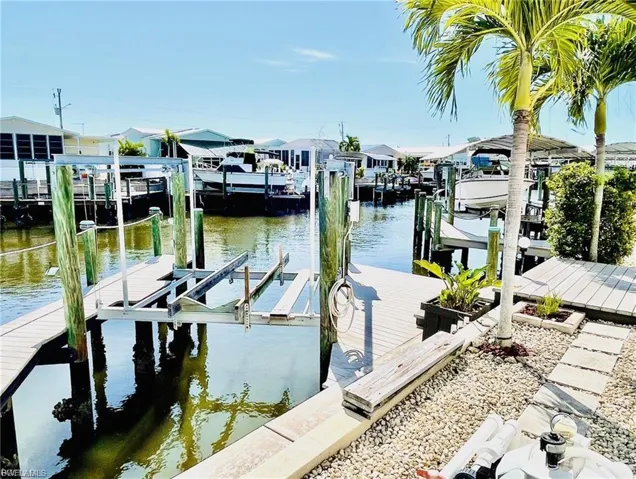 Waterfront property featuring a private boat dock with lift, direct canal access, and a stone-lined yard with mature palm trees