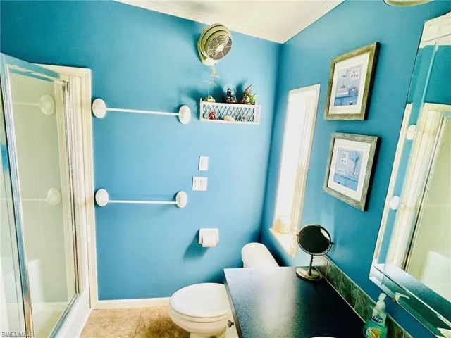 Bathroom featuring a glass-enclosed shower, a vanity with a dark countertop, an elongated window, and blue painted walls