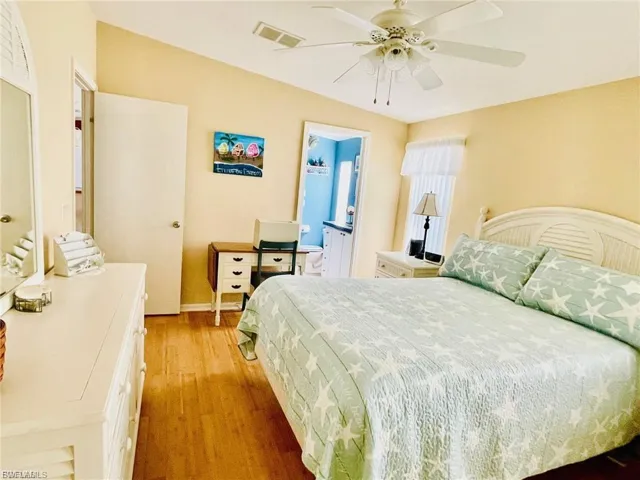 Bedroom featuring solid bamboo flooring, vaulted ceilings, and a ceiling fan with integrated lighting