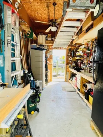 Workroom featuring a ceiling fan, exposed wood ceiling, built-in shelving, concrete flooring, and a window providing natural light