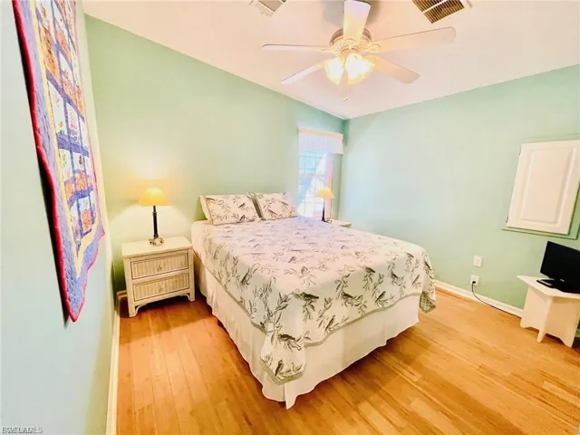 Bedroom featuring solid bamboo wood flooring, a ceiling fan with integrated lighting, and a window with a white blind