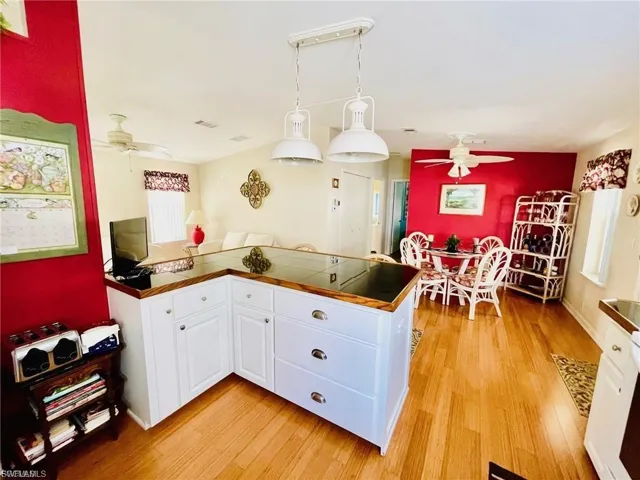 Kitchen island featuring white cabinetry with silver hardware, a dark countertop, and wood-finish trim