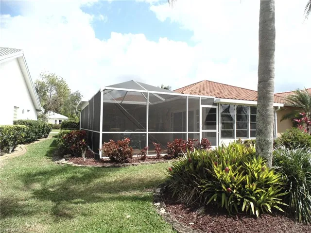 Back of property with glass enclosure, a yard, and a sunroom
