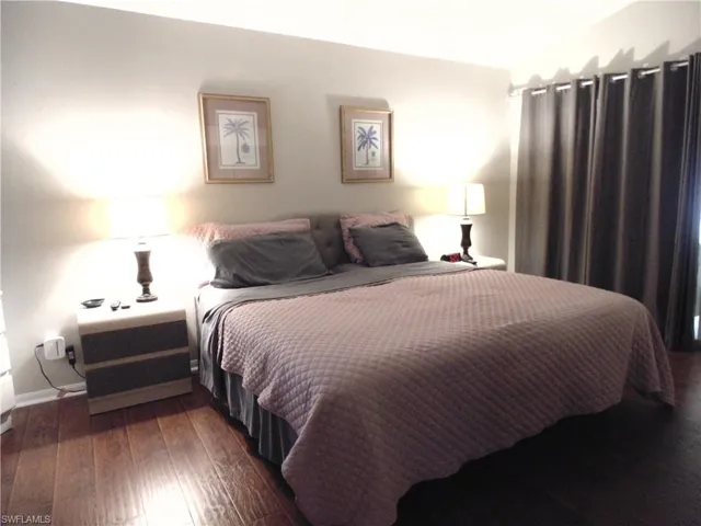 Bedroom featuring dark wood-style flooring and baseboards