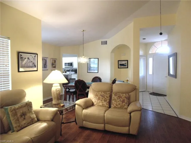 Living area with hardwood / wood-style floors, a chandelier, high vaulted ceiling, and arched walkways