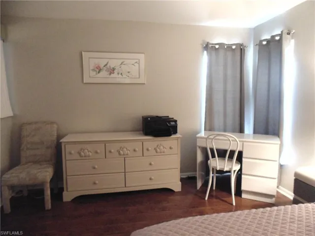 Bedroom with dark wood-style floors and a desk