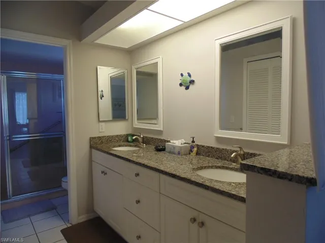 Full bath with double vanity, a stall shower, and light tile patterned floors