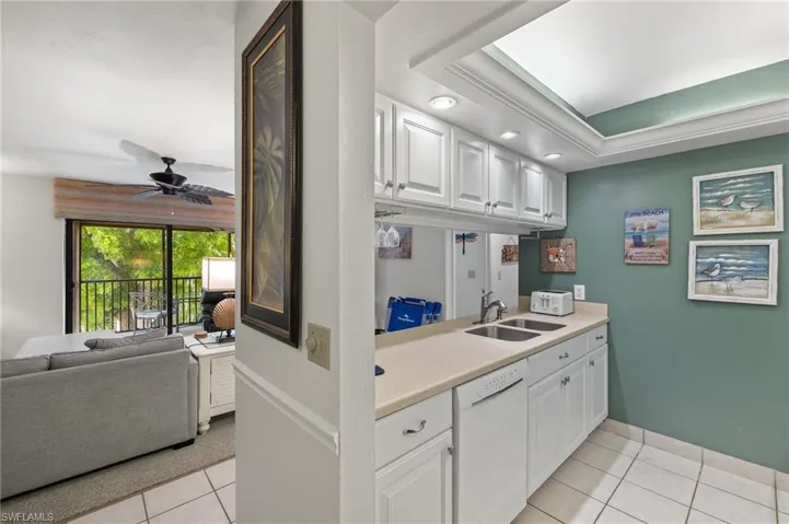 Kitchen featuring light tile patterned flooring, white dishwasher, light countertops, white cabinetry, and a ceiling fan