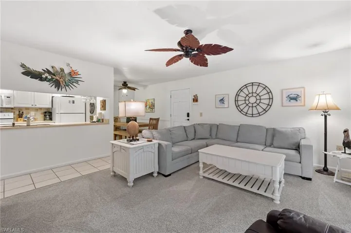 Living room featuring ceiling fan, light colored carpet, and light tile patterned flooring