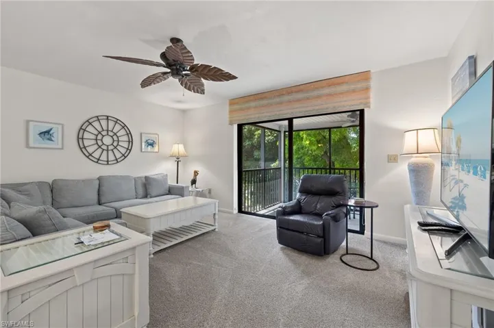 Carpeted living room featuring ceiling fan and baseboards