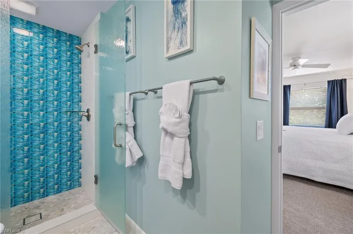 Full bath with connected bathroom, a stall shower, and ceiling fan