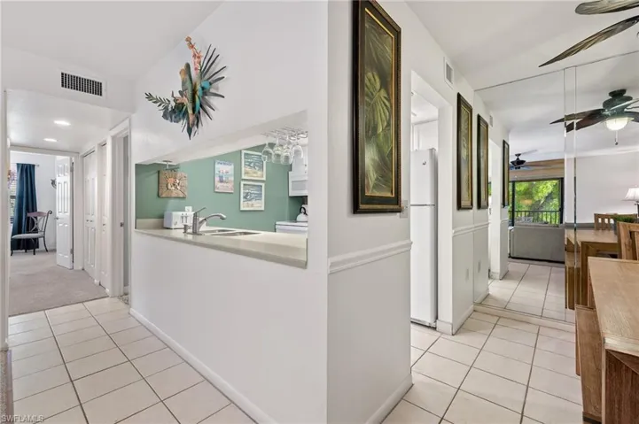 Corridor with light tile patterned flooring and a sink