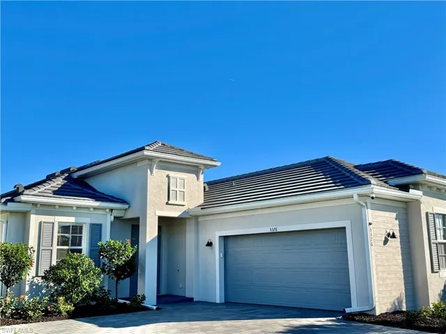 View of front of property featuring driveway, stucco siding, an attached garage, and brick siding