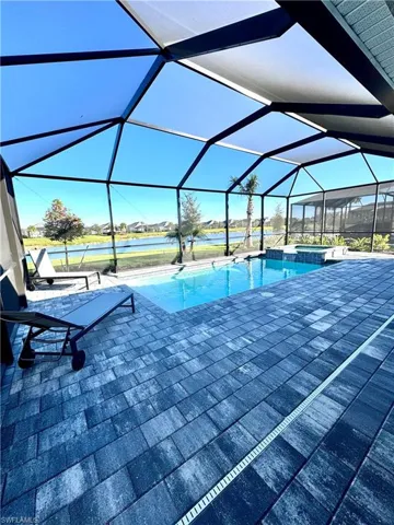 View of swimming pool with a sunroom, a pool with connected hot tub, screen enclosure, and a water view