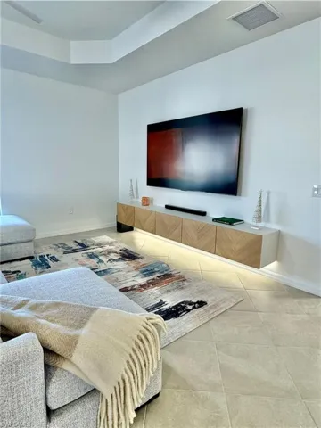 Tiled living area featuring baseboards and a tray ceiling