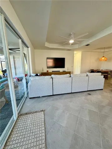 Living area with ceiling fan and a raised ceiling