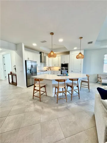 Kitchen featuring a breakfast bar area, stainless steel appliances, white cabinets, hanging light fixtures, and recessed lighting