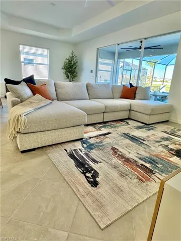 Tiled living room with a tray ceiling and a ceiling fan