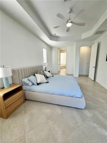 Bedroom with a ceiling fan and a raised ceiling