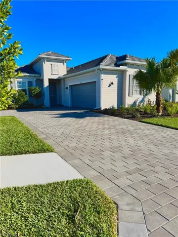 View of front of house with a garage, decorative driveway, stucco siding, and a tiled roof