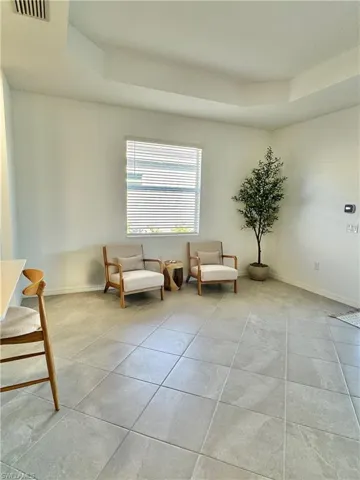 Living area featuring a tray ceiling and light tile patterned floors