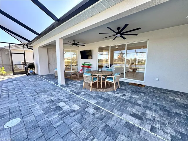 View of patio with a sunroom, a ceiling fan, outdoor dining area, and a lanai