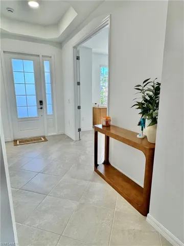 Foyer entrance featuring a raised ceiling and light tile patterned floors