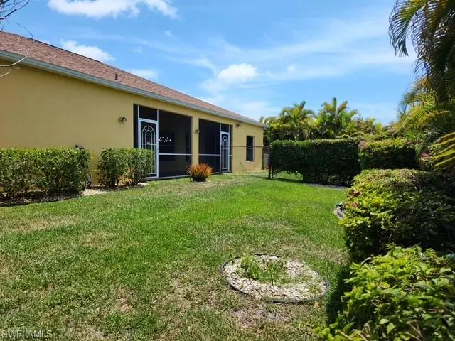 Expansive backyard featuring a manicured lawn, screened patio, and mature landscaping