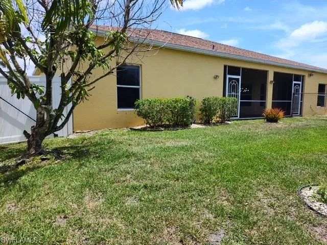 Expansive green lawn with mature landscaping and a white privacy fence