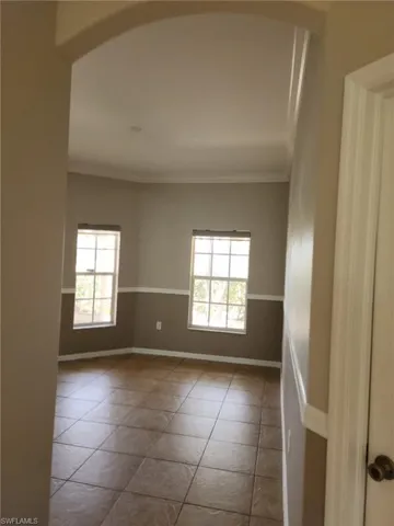 Tiled flooring in a room featuring two windows and crown molding