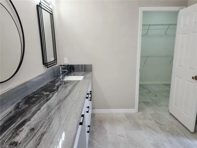 Bathroom vanity featuring a single undermount sink and a stone countertop with prominent veining