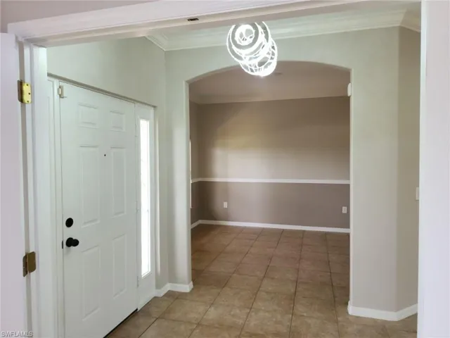 Entryway featuring a white paneled door with sidelight, tile flooring, and an arched opening to an interior space, foyer and Formal dining room