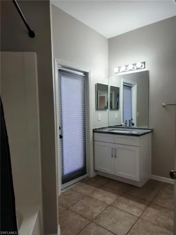 Bathroom featuring a single vanity with white cabinetry, dark countertop, and an integrated sink with a chrome faucet