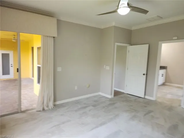 Spacious room featuring light gray tile flooring, crown molding, and a modern ceiling fan
