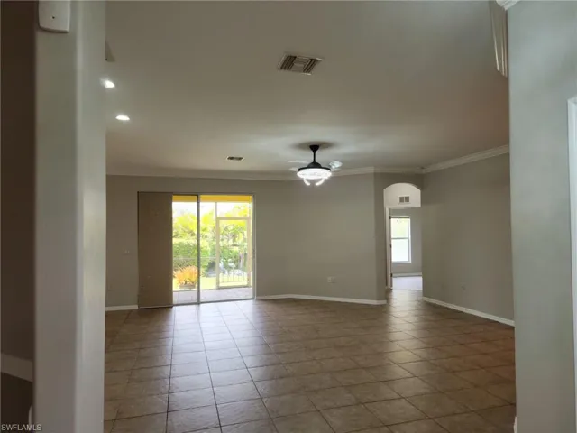 Spacious interior featuring tile flooring, neutral wall tones, recessed lighting, and crown molding