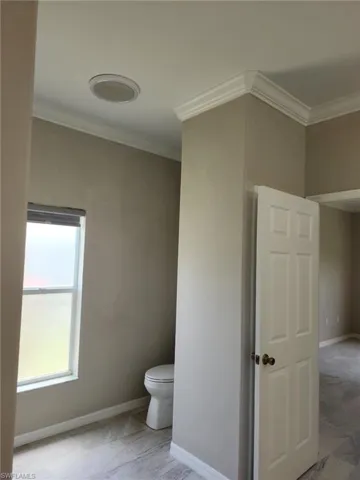 Neutral-toned interior featuring crown molding and a ceiling-mounted light fixture