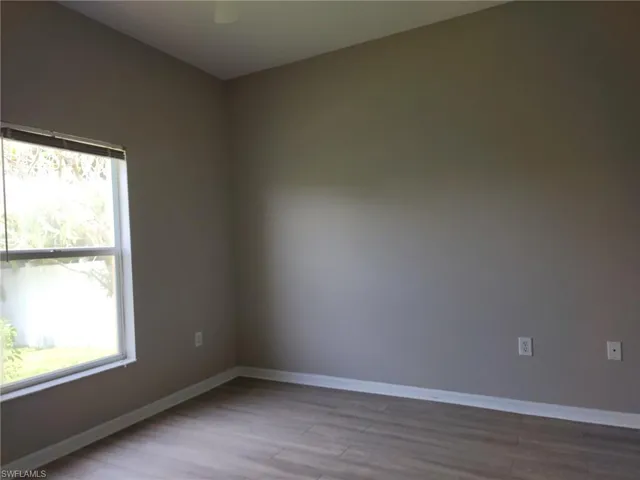 Neutral-toned interior with wood-finish flooring, a white window frame, and baseboard trim