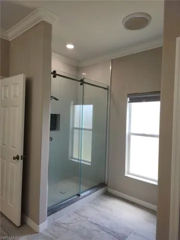 Spacious shower enclosure with clear glass sliding doors and a dark stone threshold
