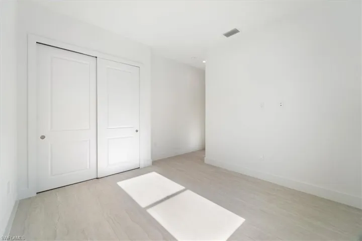 Unfurnished bedroom featuring a closet, baseboards, visible vents, and light wood-type flooring