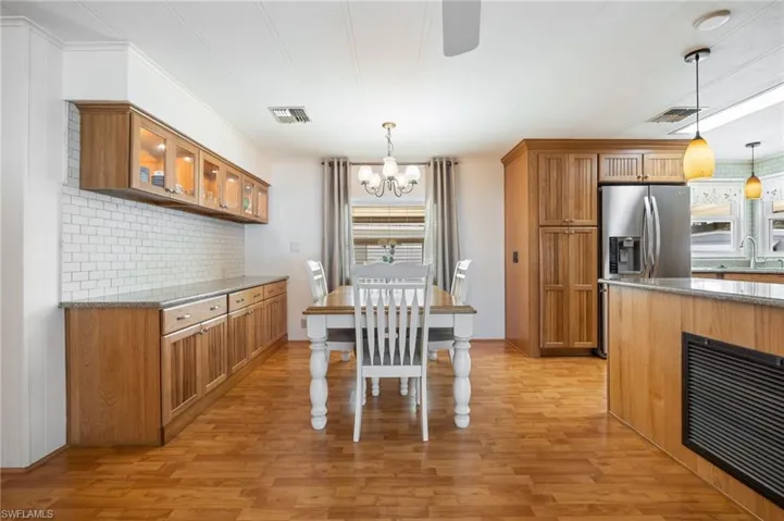 Kitchen featuring dark stone counters, wood finish cabinetry, light wood-style floors, and hanging lights
