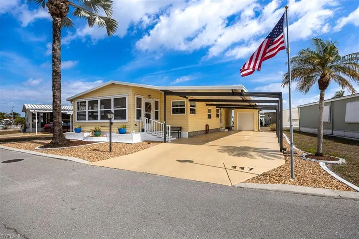 Manufactured / mobile home with a carport, a sunroom, driveway, and a patio