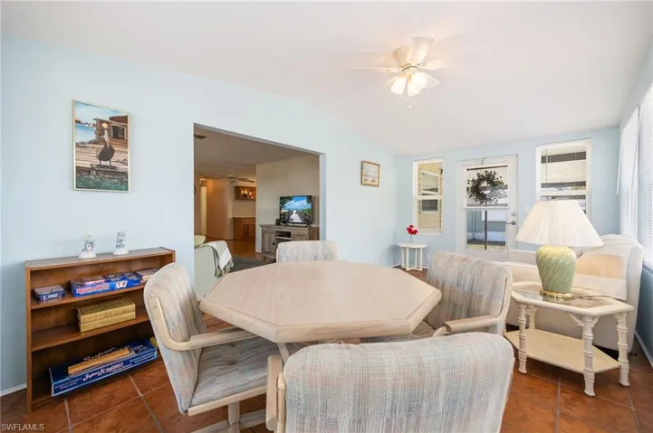 Dining space featuring ceiling fan, dark tile patterned floors, and lofted ceiling